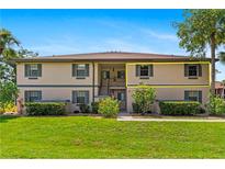 Condo building exterior with manicured lawn, vibrant green shrubs and neutral color palette against a clear, sunny sky at 19505 Quesada Ave # Vv201, Port Charlotte, FL 33948
