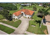 Aerial view of a home with a tile roof, long driveway, and lush landscaping on a sunny day at 2105 Deborah Dr, Punta Gorda, FL 33950