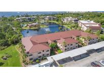 Stunning aerial view of a Roll's Landing condo community, showcasing lake, mature trees, and well-maintained buildings at 23465 Harborview Rd # 214, Punta Gorda, FL 33980
