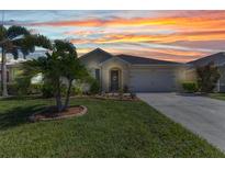 Inviting single-story home featuring a well-manicured lawn, tasteful landscaping, and a warm, neutral color palette at 25272 E Lenox Cir, Punta Gorda, FL 33950