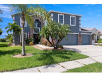 Charming two-story home featuring a three-car garage, well-manicured lawn, and mature landscaping at 2736 Suncoast Lakes Blvd, Punta Gorda, FL 33980