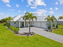Beautiful single-story home with lush landscaping, a metal roof, and a paved driveway at 28960 Gin Ln, Punta Gorda, FL 33982