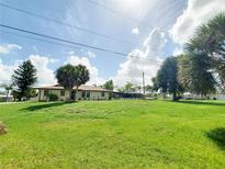 Charming single-story home with a large front lawn and mature trees under a partly cloudy sky at 3456 Highlands Rd, Punta Gorda, FL 33983
