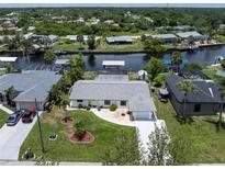 Waterfront home featuring a private dock with a boat lift, lush landscaping, and a well-maintained yard at 4051 Rock Creek Dr, Port Charlotte, FL 33948