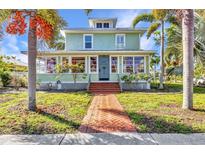 Charming two-story home with a brick walkway, lush landscaping, and inviting front porch at 415 W Marion Ave, Punta Gorda, FL 33950