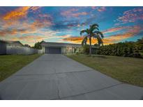 Charming single-story home featuring a well-manicured lawn and a spacious driveway leading to an attached two-car garage at 457 Glenridge Nw Ave, Port Charlotte, FL 33952