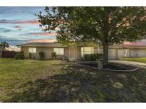Charming single-story home featuring well-kept landscaping and a cozy, inviting facade under a colorful sunset sky at 496 Fletcher St, Port Charlotte, FL 33954