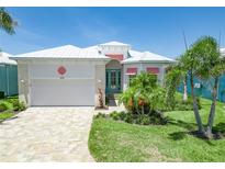 Charming single-story home showcasing a white metal roof, landscaped front yard, and two-car garage at 10478 Coquina Ct, Placida, FL 33946