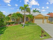 Beautiful home featuring a well-manicured lawn, palm trees, and a two-car garage at 1323 Mineo Dr, Punta Gorda, FL 33950