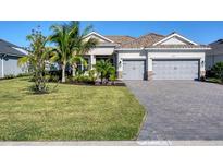Charming one-story home featuring a tile roof, brick driveway, lush landscaping, and a two-car garage at 14436 Ponce De Leon Trl, Port Charlotte, FL 33981