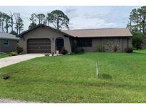 Charming single-story home featuring an attached garage and well-maintained lawn at 18094 Ackerman Ave, Port Charlotte, FL 33948