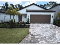 Charming single-story home with a well-manicured lawn, brick driveway, and attached two-car garage at 1992 Sunset Preserve Way, Port Charlotte, FL 33953