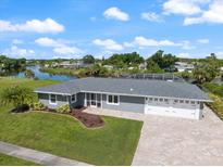 Beautiful single-story home featuring an attached three-car garage, landscaped yard, and waterfront views at 2309 Conway Blvd, Port Charlotte, FL 33952