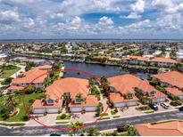 Stunning aerial view of a waterfront townhome featuring a red tile roof and lush tropical landscaping at 2630 Tarpon Cove Dr # 211, Punta Gorda, FL 33950