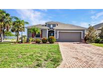 Beautiful single-story home with manicured lawn, brick driveway, and lush landscaping at 27896 Arrowhead Cir, Punta Gorda, FL 33982