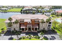 Beautiful condo building with terracotta tile roof, palm trees, manicured lawn, and views of the bay at 3308 Purple Martin Dr # 121, Punta Gorda, FL 33950