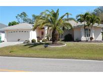 Charming single-story home featuring a well-manicured lawn, mature palm trees, and a two-car garage at 388 Orlando Blvd, Port Charlotte, FL 33954