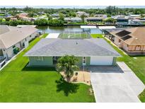Waterfront home with a well-manicured lawn, mature palm tree, and a screened lanai for seamless indoor-outdoor living at 4123 Rock Creek Dr, Port Charlotte, FL 33948
