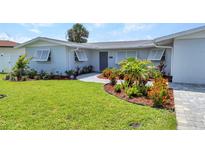 Charming single-story home featuring a beautifully landscaped front yard with colorful plants and fresh green grass at 4244 Harbor Blvd, Port Charlotte, FL 33952