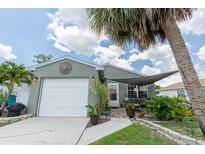 Charming home featuring a light green exterior, a one-car garage, and a cozy front porch at 477 Ricold Ter, Port Charlotte, FL 33954