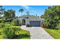 Charming single-story home with a two-car garage, brick driveway, and lush landscaping at 149 Crevalle Rd, Rotonda West, FL 33947