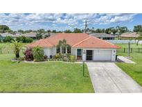 Charming home featuring lush landscaping, a vibrant tile roof, and a well-manicured lawn at 23141 Corvin Ave, Port Charlotte, FL 33954