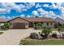 Charming single-story home with a paver driveway, lush landscaping, and a two-car garage at 2814 La Mancha Ct, Punta Gorda, FL 33950