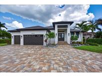 Stunning single-story home with a three-car garage, beautiful landscaping, and a paver driveway at 3800 Carupano Ct, Punta Gorda, FL 33950