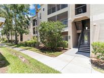 Tan condo building featuring outdoor stairwell, landscaped grounds, and sidewalks at 5146 Northridge Rd # 305, Sarasota, FL 34238