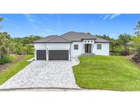 Beautiful new construction home with a paver driveway, two-car garage, and lush landscaping at 576 Mcdill Dr, Port Charlotte, FL 33953