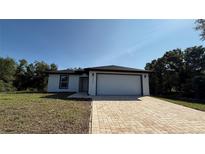 Charming single-story home featuring a brick driveway, a two-car garage, and a well-maintained front lawn at 7052 Legion St, Port Charlotte, FL 33981