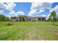 Expansive single-story home featuring a metal roof, neutral stucco, stone accents, and a large green lawn under a blue sky at 8312 Acorn Blvd, Punta Gorda, FL 33982
