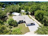 Bright ranch-style home with lush trees, detached garage, and long driveway at 875 Bayshore Dr, Englewood, FL 34223