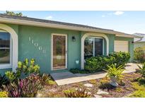 Inviting home entrance with vibrant foliage, glass door and decorative house numbers at 11068 Jacqueline Ave, Englewood, FL 34224