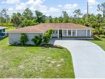 Charming single-story home with a well-manicured lawn, long driveway, and a welcoming facade at 123 Annapolis Ln, Rotonda West, FL 33947