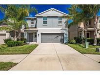 Charming two-story home featuring a gray color scheme, attached two-car garage, and tropical landscaping at 17032 Yellow Pine St, Wimauma, FL 33598