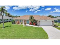 Charming single-story home with a well-manicured lawn and a welcoming turquoise front door at 1915 Pebble Beach Ct, Venice, FL 34293