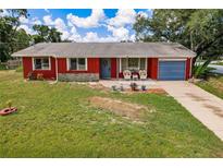 Charming single-story home features a vibrant red exterior, blue garage door, and well-maintained lawn at 20409 Emerald Ave, Port Charlotte, FL 33952
