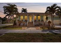 Charming coastal home featuring mature palms, a welcoming porch and lush landscaping at 233 Durrance St, Punta Gorda, FL 33950