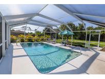 Beautiful screened-in pool with lounge seating, umbrella table and lush landscaping at 3270 Ithaca St, Port Charlotte, FL 33952