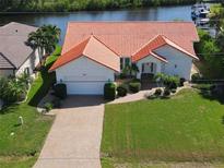 Beautiful waterfront home featuring a red tile roof, attached garage, and lush landscaping at 3588 Tripoli Blvd, Punta Gorda, FL 33950