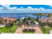 Stunning waterfront home with lush landscaping, brick driveway, and picturesque water views at 119 Creek Se Dr, Port Charlotte, FL 33952
