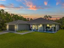 Charming single-story home featuring a spacious lawn, covered porch, and two-car garage at 12300 El Prado Dr, Punta Gorda, FL 33955