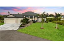 Beautiful single-story home featuring a lush lawn, two-car garage and a covered entryway with decorative wreaths at 12581 Eisenhower Dr, Port Charlotte, FL 33953