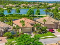 Beautiful single-Gathering home boasts a tile roof, a two-car garage, and verdant landscaping overlooking a serene lake at 13136 N Marsh Dr, Port Charlotte, FL 33953