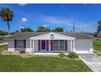 Charming single story home with purple shutters, an attached garage, and a well-maintained front lawn at 1389 Hinton St, Port Charlotte, FL 33952