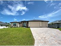 Charming single-story home with a three-car garage, beautiful stone accents, and a well-manicured lawn at 15741 Autry Cir, Port Charlotte, FL 33981