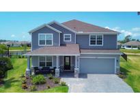 Charming two-story home with a well-manicured lawn, a covered porch, and an attached two-car garage at 16833 Terrapin Key Dr, Port Charlotte, FL 33953