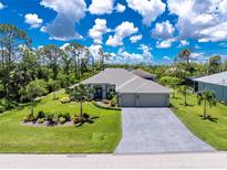 Beautiful single-story home with a well-manicured lawn, mature trees, and a spacious three-car garage at 185 Hercules Dr, Rotonda West, FL 33947