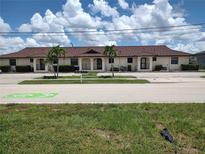 Low-rise condo building with beige stucco and terra cotta tile roof, palm trees and lush green landscaping at 2732 Magdalina Dr # C, Punta Gorda, FL 33950
